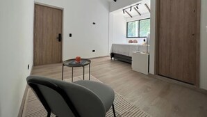 A modern room with a bed, a small table, a chair, and a window with a view. - Apartamento Hija Mía (Medellín)