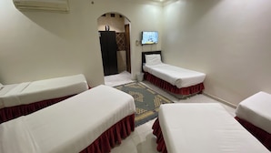 A hotel room with two single beds, a TV, an air conditioning unit, and a small rug. - nazal alroh alhora -Hajj Street (Makkah)