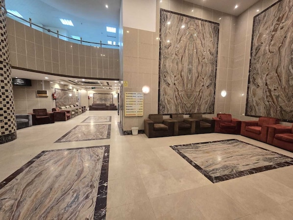 A spacious lobby with marble flooring, a seating area with sofas, and a large wall-mounted artwork.
