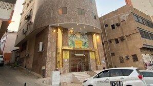 A tall, cylindrical hotel with a modern design, featuring a prominent entrance with a decorative facade and a staircase leading to the entrance. - nazal alroh alhora -Hajj Street (Makkah)
