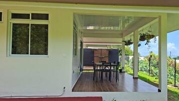 A house with a covered patio, a dining area with chairs and a table, and a red step leading to the entrance.