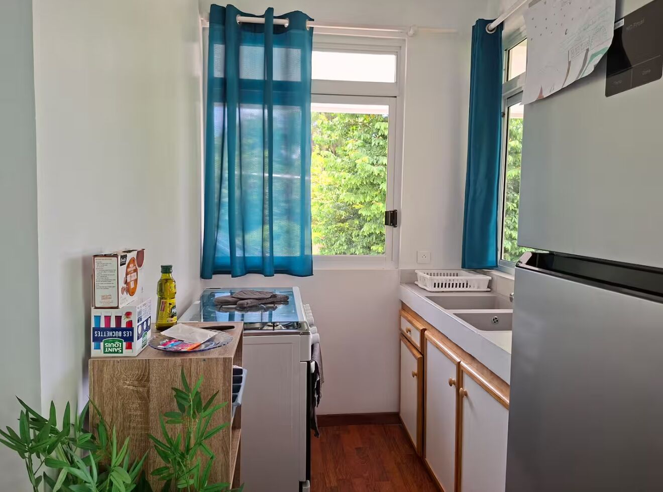 Une cuisine de taille réduite équipée d’une cuisinière à gaz, d’un évier et d’un réfrigérateur.