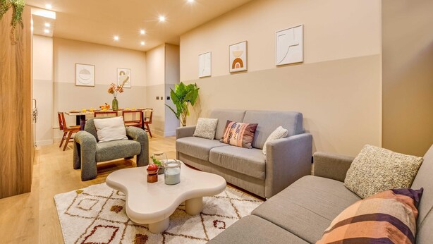A modern living room with a grey sofa, a white coffee table, and a dining area with a wooden table and chairs. - Spacious Apartment - 2br/10p - Place D'italie (Paris)