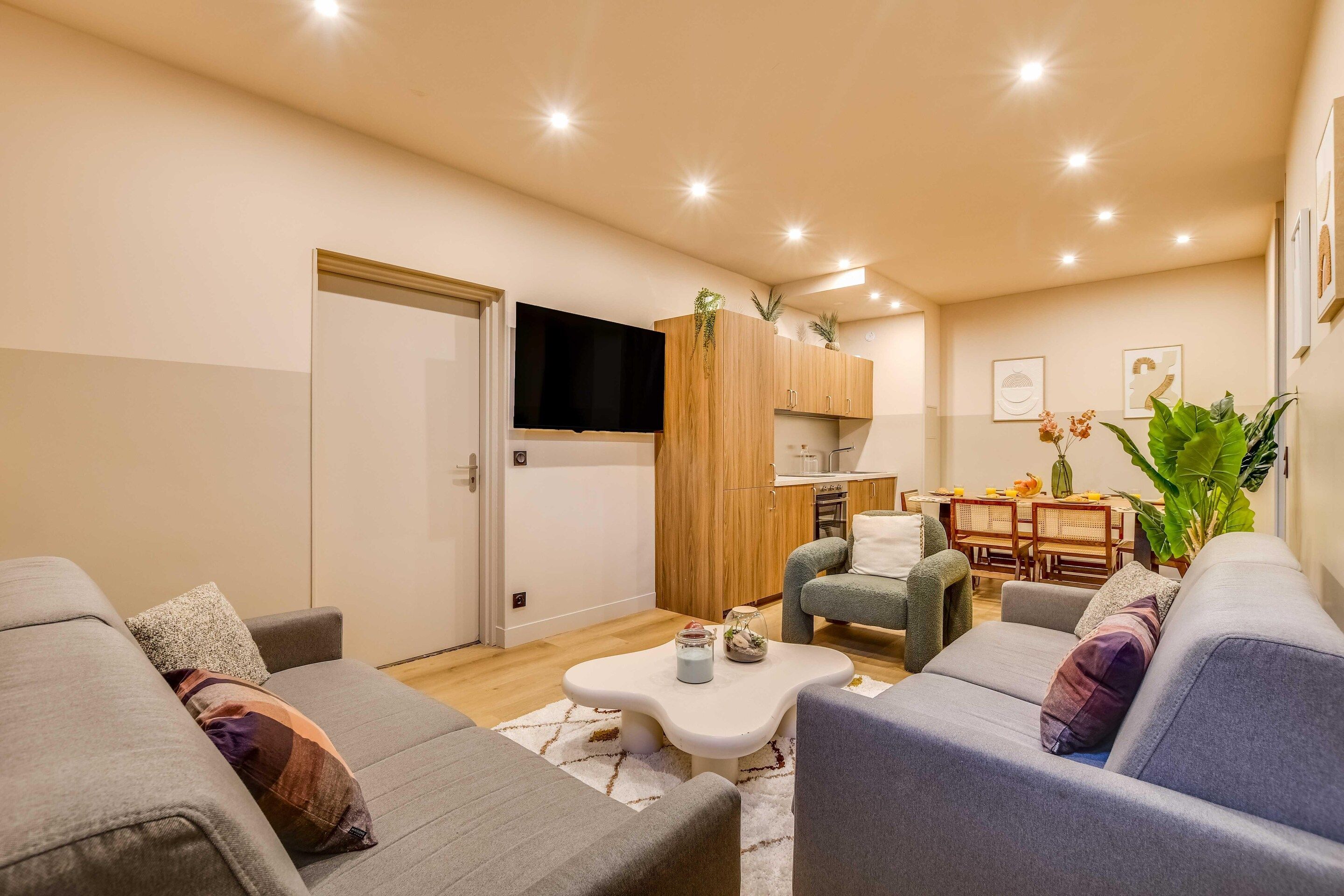 Ein modernes Wohnzimmer mit einer Couch, einem Couchtisch und einem Essbereich mit Stühlen und einem Tisch.