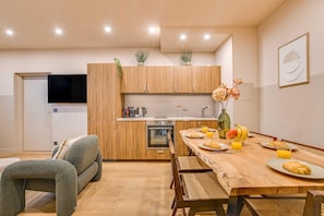 A modern kitchen with wooden cabinets, a built-in oven, and a dining area with a wooden table and chairs. - Spacious Apartment - 2br/10p - Place D'italie (Paris)