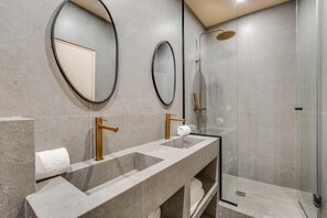 Ein modernes Badezimmer mit einem Doppelwaschtisch, einer begehbaren Dusche und zwei wandmontierten Spiegeln.