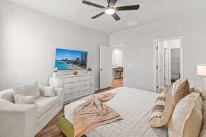 Un dormitorio con cama, sofá blanco, ventilador de techo y una pintura de un paisaje urbano.