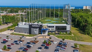A golf course with a TopGolf building, parking lot, and surrounding greenery. - Cozy Escape Retreat – Luxury Brand New 3BR/3BA (Myrtle Beach)