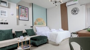 Habitación de hotel moderna con una cama, un sofá, una mesita y un aire acondicionado de pared.