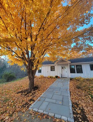 A house with a pathway leading to the front door, surrounded by autumn foliage. - River House- Belfast Maine (Belfast)
