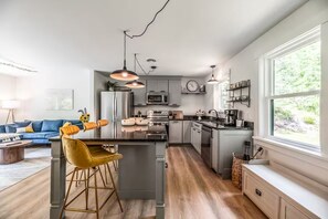 Een moderne keuken met een centraal eiland, barstoelen, hanglampen en uitzicht op de omgeving.