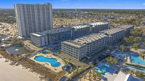 Ein mehrstöckiges Hotel mit Poolbereich und Zugang zum Strand.