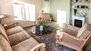 A living room with patterned sofas, a round table, a vase with flowers, a fireplace, and a shelf with decorative items. - Holiday Home in Konz (Konz)