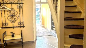 A staircase with a handrail, a chair with a potted plant, and a decorative metal piece on the wall. - Holiday Home in Konz (Konz)