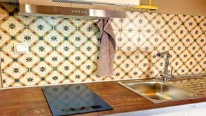 A kitchen with patterned tiles, a stainless steel sink, and a wooden countertop. - Gemütliche Wohnung in Konz an der Mosel (Konz)