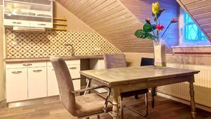 A dining area with a table and chairs, a kitchen with patterned backsplash, and a window with a view. - Gemütliche Wohnung in Konz an der Mosel (Konz)