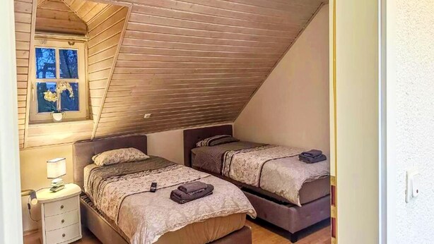 A bedroom with two beds, a window with a view, and a wooden ceiling. - Gemütliche Wohnung in Konz an der Mosel (Konz)