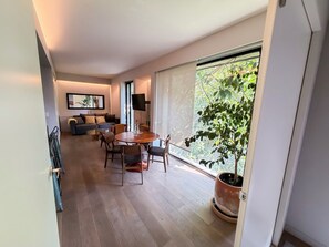 A modern living room with a dining area, large windows, and a potted plant. - Cute, modern apartment • 24/7 Doorman Safe + Secure • Walk everywhere (Ciudad de México)
