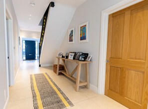 Ein Flur mit einer Holztür, einer Treppe und einer Wandvitrine mit Fotos.