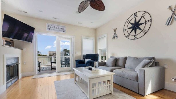 A living room with a grey sofa, a white coffee table, a flat-screen TV mounted on the wall, and a 'WELCOME' sign. - Coastal Cabana, an island escape (Carolina Beach)