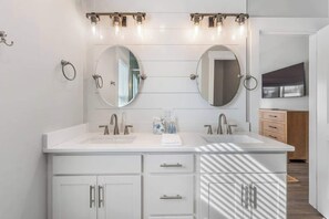 Ein modernes Badezimmer mit zwei Waschbecken, einem Waschtisch mit Schubladen und einem Spiegel über jedem Waschbecken.