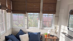 A modern living room with a sectional sofa, a small wooden table, and a large window with blinds.
