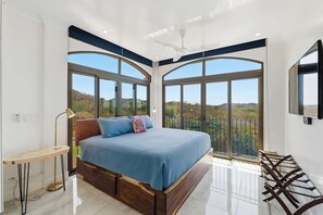 Ein Schlafzimmer mit einem großen Bett, einem Schreibtisch und einem Balkon mit Blick.