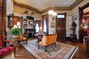 A traditional room with a fireplace, wooden furniture, a large rug, and a chandelier.