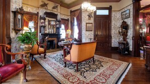 Una habitación tradicional con chimenea, muebles de madera y un tapete grande.