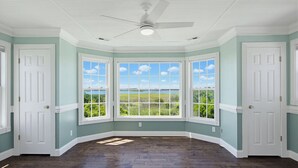 Ein Zimmer mit Erkerfenster, weißen Türen und Deckenventilator.