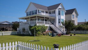 Ein zweistöckiges Haus mit Balkon, Veranda und einer Treppe, die zum zweiten Stock führt.