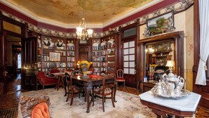 Una biblioteca con elaborada carpintería, un candelabro y un juego de té de plata grande sobre una mesa.