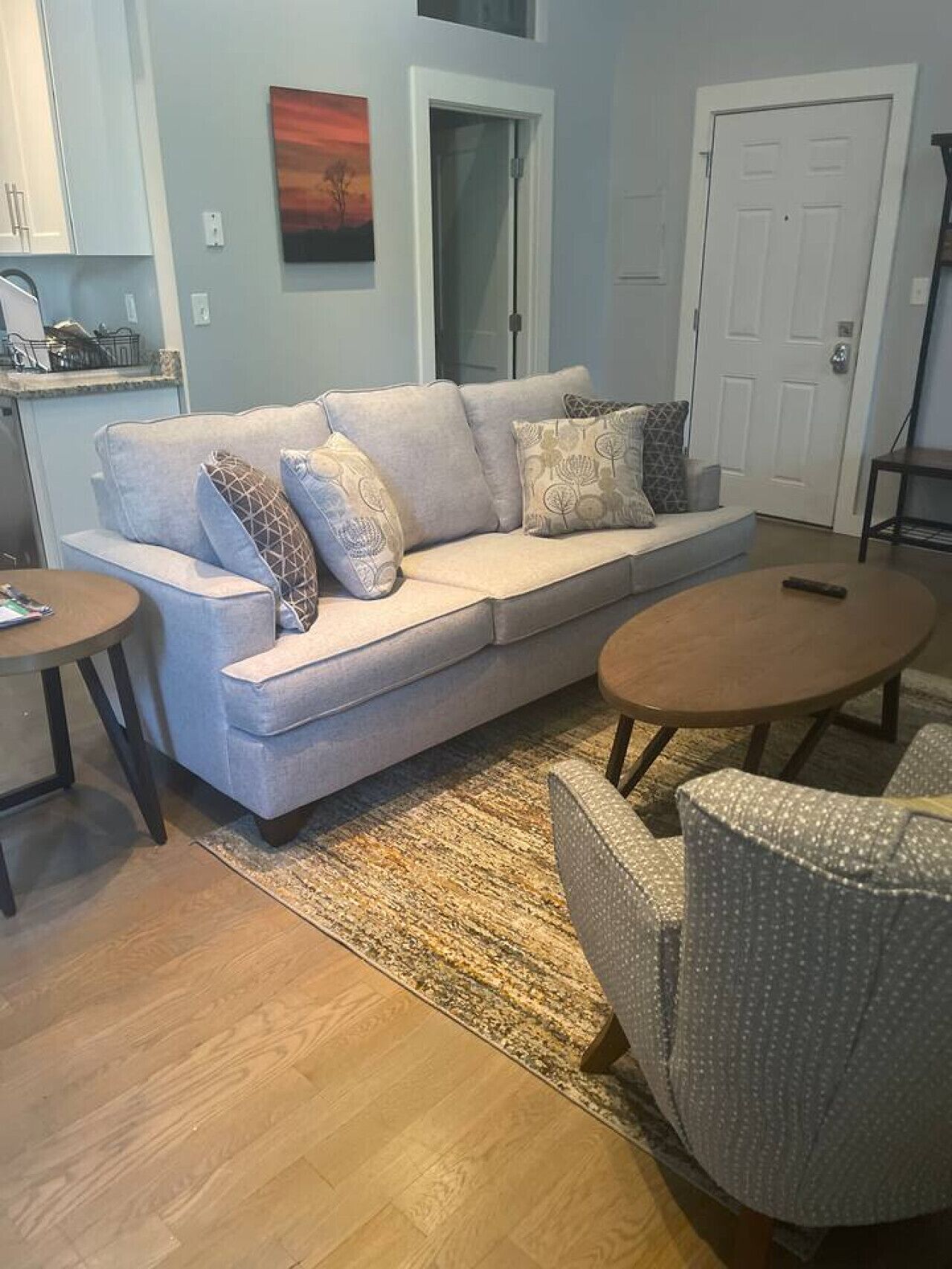 A living room with a light-colored sofa, patterned cushions, a small round table, and a patterned rug.