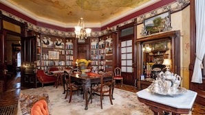 Una biblioteca con elaborate decorazioni in legno intagliato, un lampadario e un servizio da tè d'argento su un tavolo.