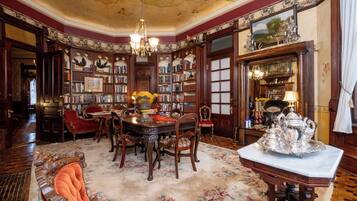 A library with ornate woodwork, a chandelier, and a large silver tea service on a table.