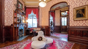 Una sala maestosa con carta da parati decorata, una grande poltrona, un camino e un lampadario.