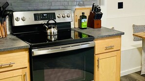 A kitchen with a stove, oven, and various utensils. - Cozy Two Bedroom on Munjoy Hill (Portland)