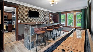 Eine Bar mit Hockern, ein Billardtisch und eine Küche mit modernen Geräten.