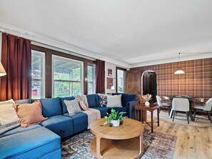 Ein Wohnzimmer mit einem blauen Sofa, einem Holztisch und einem Essbereich mit Tisch und Stühlen.