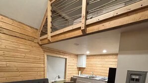 Quarto estilo loft com sofá, mesa de jantar e cozinha.