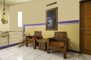 Une pièce avec une porte en bois, une fenêtre avec des rideaux, une lampe suspendue et un sol carrelé.
