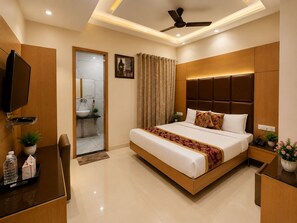A modern hotel room with a bed, bedside table, TV, and a bathroom visible through an open door. - THE KING HAWK Nearby GOLDEN TEMPLE (Amritsar)