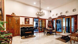 Un'ampia stanza con un pianoforte, un lampadario e un'area da pranzo con tavolo e sedie.
