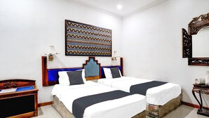 Camera d'albergo con due letti, un grande pannello decorativo, uno specchio e un comodino in legno.