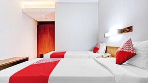Ein Hotelzimmer mit zwei Betten, einem hölzernen Nachttisch, einem Telefon und einer Wandleuchte.