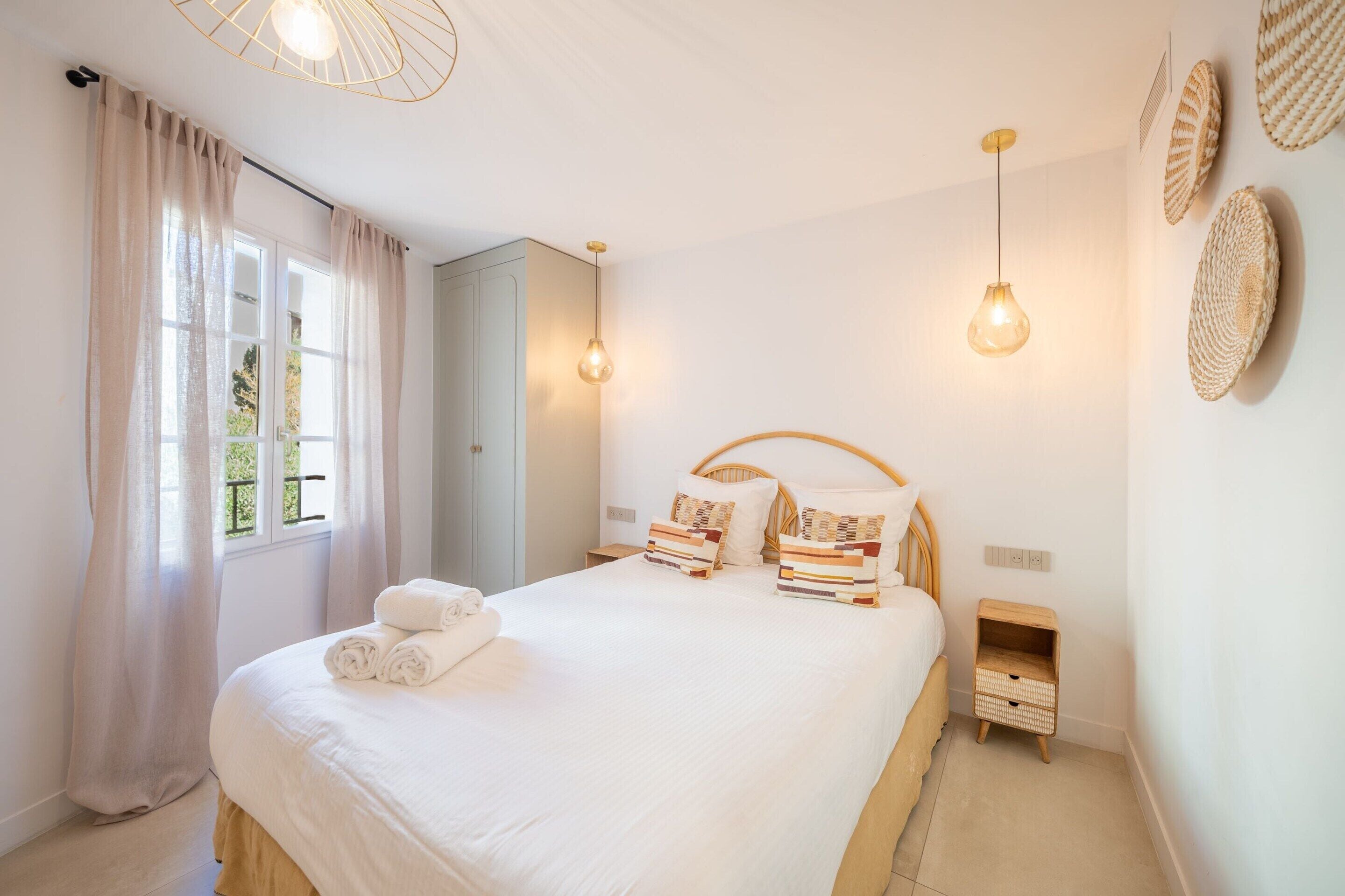 A bedroom with a bed, bedside tables, a wardrobe, and a window with curtains.