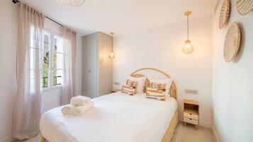 A bedroom with a bed, bedside tables, a wardrobe, and a window with curtains.