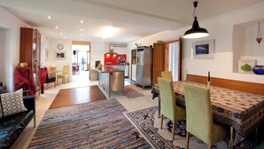 Una sala de estar moderna con sofá, una mesa de comedor con sillas, una zona de cocina con refrigerador y una silla roja.