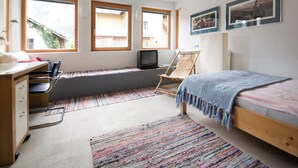 Un dormitorio con escritorio, cama, silla y ventana.
