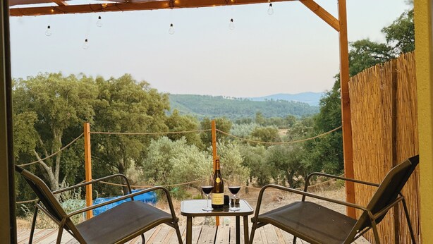 An outdoor seating area with a table and chairs, a bottle of wine, and glasses. - Beira Baixa family retreat with mountain views, AC / breakfast! (Telhado)